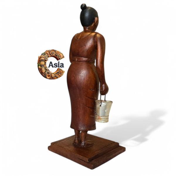 Back view of vintage wooden village woman figurine holding a bucket, handcrafted from solid wood